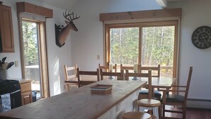 Una cucina con isola centrale, sedie di legno e un'ampia finestra vista alberi.