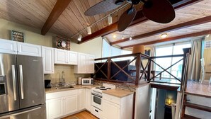 A kitchen with white cabinets, stainless steel appliances, a wooden ceiling, and a window overlooking a balcony. - Aqua Lodge Houseboat "Captain's Quarters" (Tavernier)