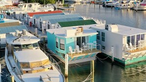 A floating houseboat docked at a marina with a covered deck and a small outdoor seating area. - Aqua Lodge Houseboat "Captain's Quarters" (Tavernier)