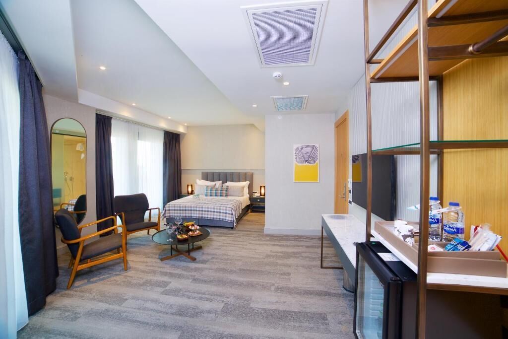 Une chambre d’hôtel équipée d’un lit, d’un bureau, d’une chaise, d’une petite table, d’un téléviseur et d’un mini-bar.