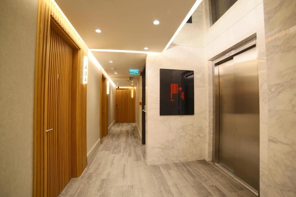 A hotel hallway with wooden doors, a marble wall, and an elevator.