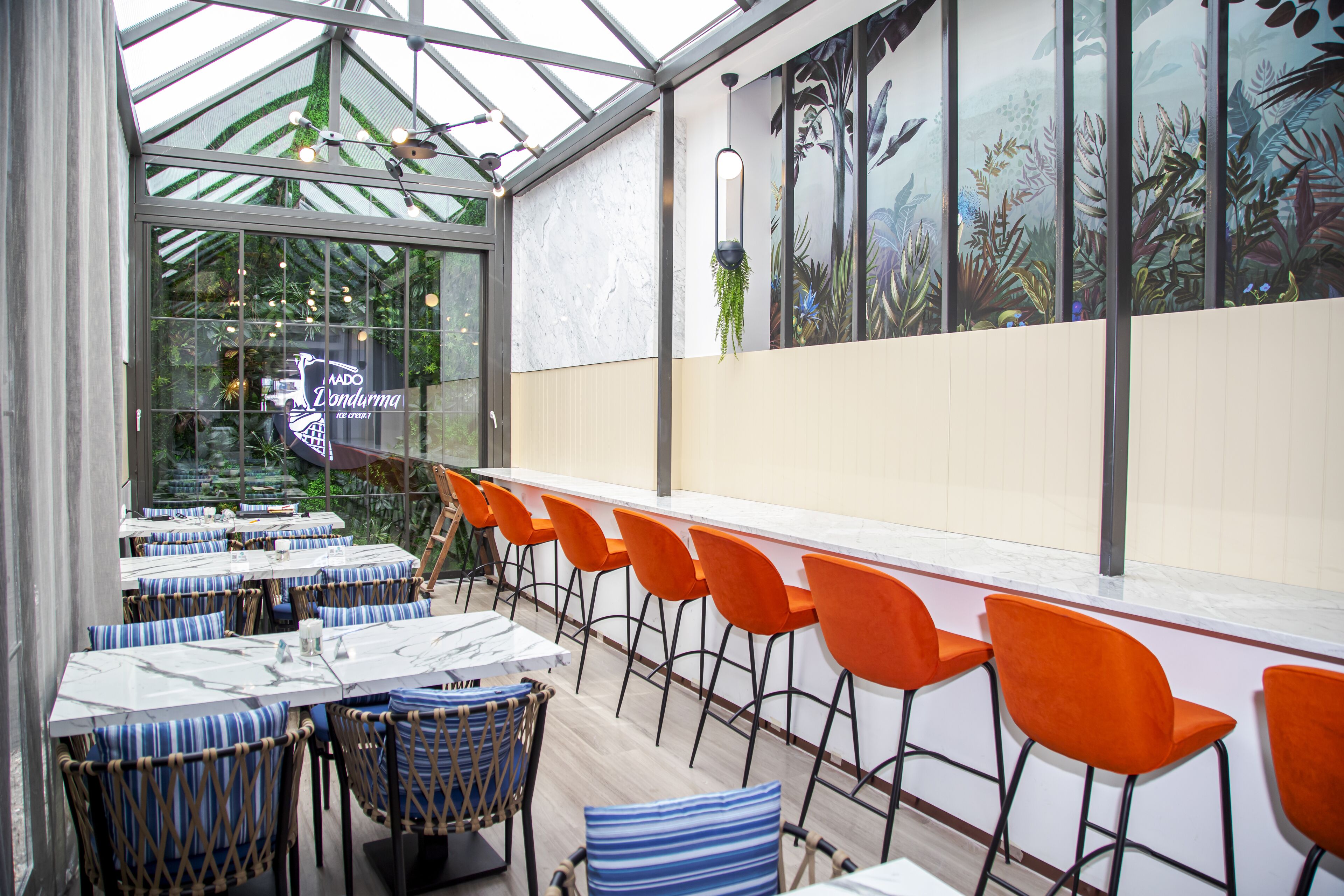 Ein Restaurant mit einer langen Theke, orangenen Stühlen und gestreiften Kissen.