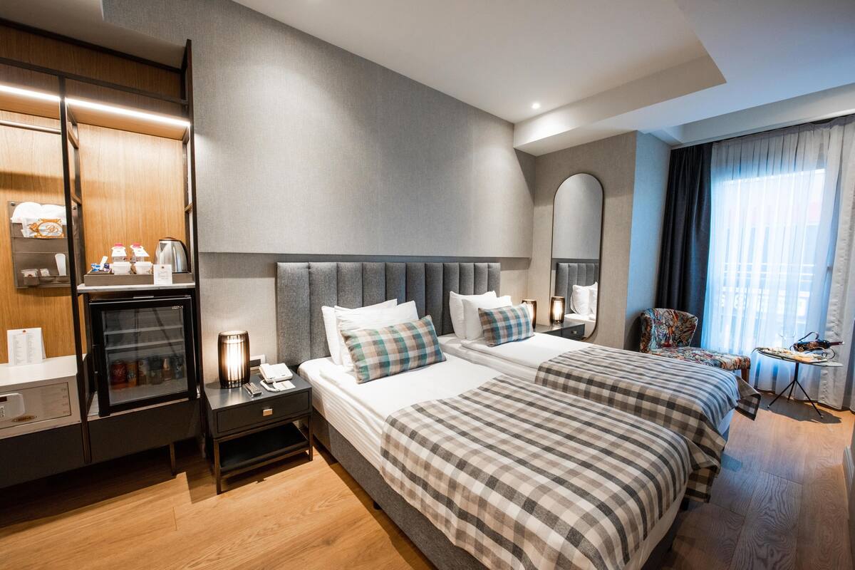A hotel room with two beds, a minibar, a desk, and a chair.
