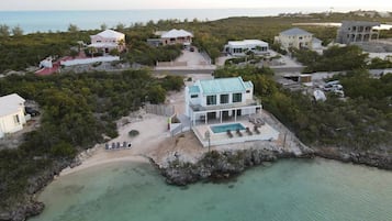 A coastal property with multiple houses, a swimming pool, and a beach.