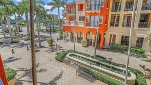 A hotel courtyard with palm trees, a fountain, and a pool. - Lavish Condo With Courtyard View, Gym, Pool and spa (Marco Island)
