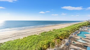 A beach resort with a swimming pool area, a sandy beach, and a clear blue sky. - Bay Watch 605-3BR/2BA Oceanfront Condo in North Myrtle Beach (North Myrtle Beach)