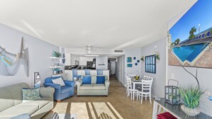 A spacious living area with a kitchen in the background, a dining table with chairs, and a poolside view. - Bay Watch 605-3BR/2BA Oceanfront Condo in North Myrtle Beach (North Myrtle Beach)