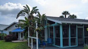 Ein Haus mit überdachter Veranda, einem Moskitonetz-Bereich und einem blauen Dach.