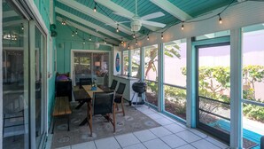 Eine überdachte Terrasse mit Esstisch, Stühlen und Deckenventilator.