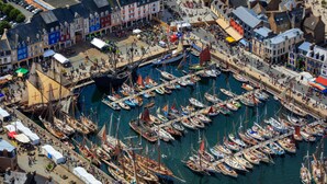 An aerial view of a harbor with numerous boats docked, surrounded by colorful buildings and a bustling waterfront area. - Cœur de Paimpol 54 m2 (Paimpol)