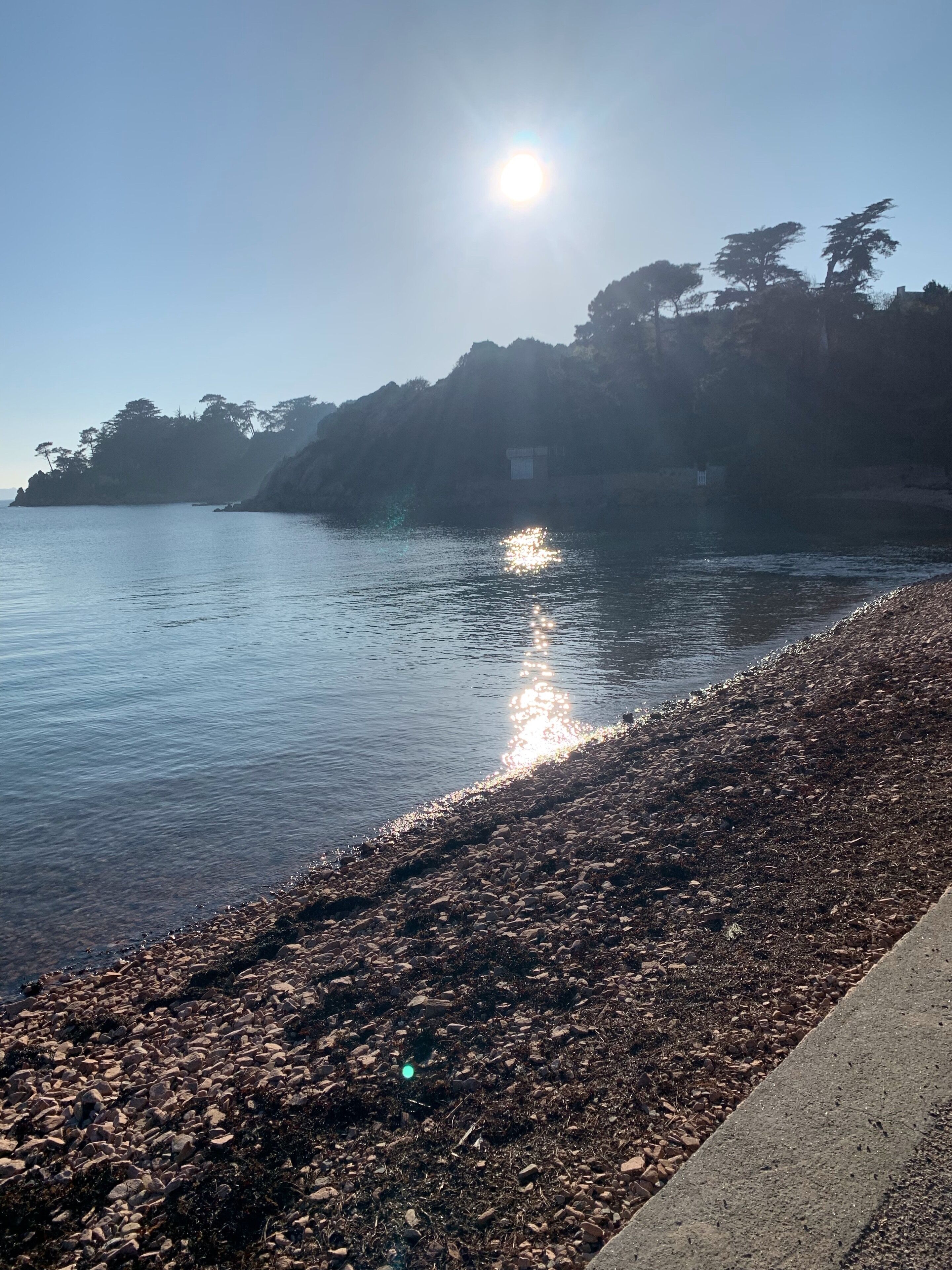A pebble beach with a clear sky and calm sea.