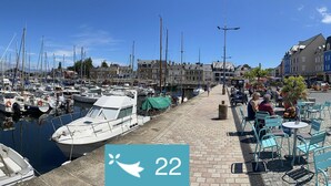 A marina with boats docked, a paved walkway, and outdoor seating areas. - Cœur de Paimpol 54 m2 (Paimpol)