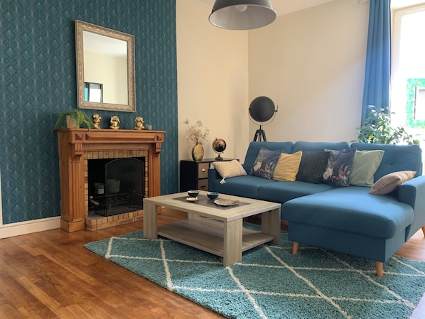 A living room with a blue sofa, a wooden coffee table, a fireplace, and a mirror on the wall.