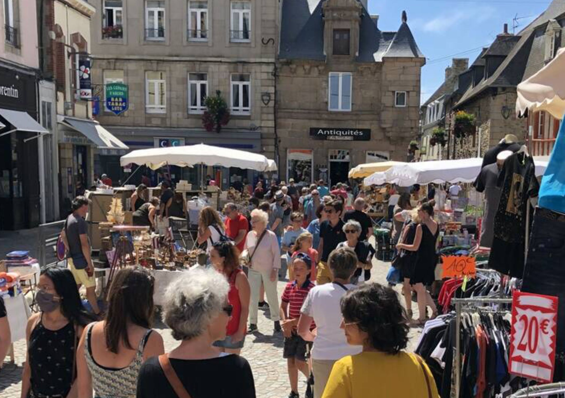 A crowded outdoor market with various stalls and people browsing.
