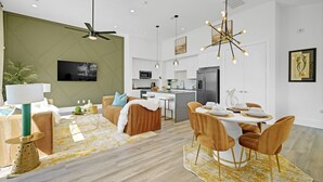 A modern kitchen with a central island, white cabinetry, and a dining area with a round table and chairs.