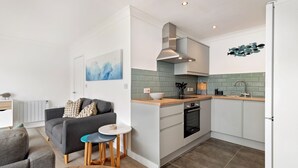 Una cocina moderna con horno empotrado, lavaplatos y estufa. Hay una zona de comedor con mesa y sillas.