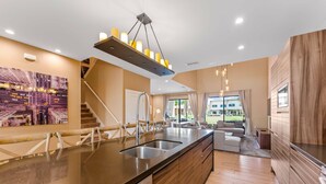Una cucina moderna con isola centrale, elettrodomestici in acciaio inossidabile e un lampadario a sospensione.