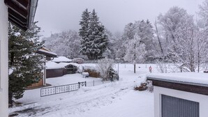 Zona residencial coberta de neu amb una casa, un garatge i un jardí també ple de neu.