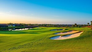 Un campo de golf con búnkeres de arena y un obstáculo acuático.