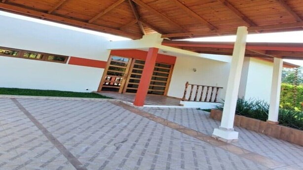 Un espacio al aire libre techado, con suelo de baldosas y estructura de techo de madera.