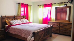 Un dormitorio con una cama de madera, una mesita de noche, un aparador y un espejo.