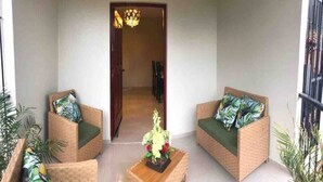 A balcony with wicker furniture, including two sofas and a small table with a flower arrangement.