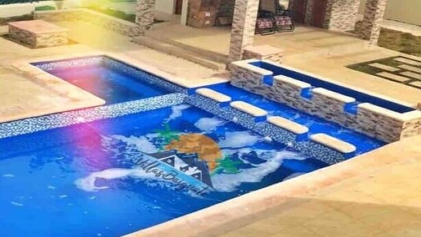 A swimming pool with a decorative design, surrounded by stone pillars and a covered seating area.