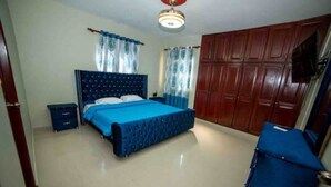 A bedroom with a bed, a wardrobe, a desk, and a chair.