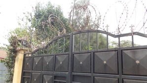 A black metal gate with decorative elements and barbed wire on top. - Stunning Villa in Private Compound in Nairobi, KE (Ongata Rongai)