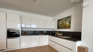 A modern kitchen with white cabinets, a black countertop, and a wooden floor. - Modernes Apartment mit Wunderschönem Rheinblick (Urmitz)
