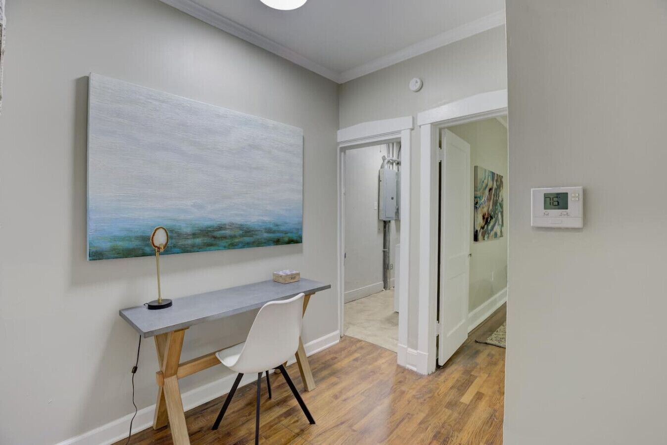 A modern office space with a desk, chair, and a large abstract painting on the wall.