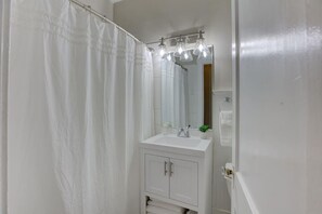 Een badkamer met een witte wastafel, spiegel en douchegordijn.