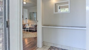 A hallway with a white wall, a ceiling fan, and a light fixture.