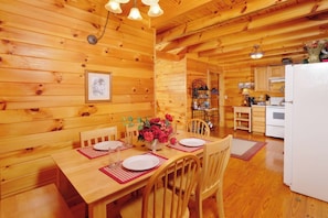 Un intérieur en bois avec une table à manger dressée pour quatre personnes, entourée de chaises en bois.