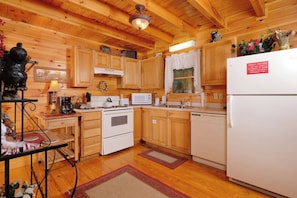 Une cuisine de style rustique, avec des éléments en bois, comprenant une cuisinière, un four à micro-ondes, un évier et un réfrigérateur.