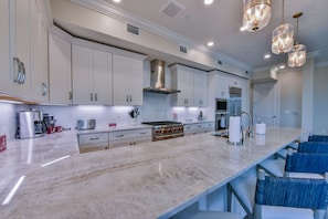 A modern kitchen with white cabinets, stainless steel appliances, and a marble countertop.