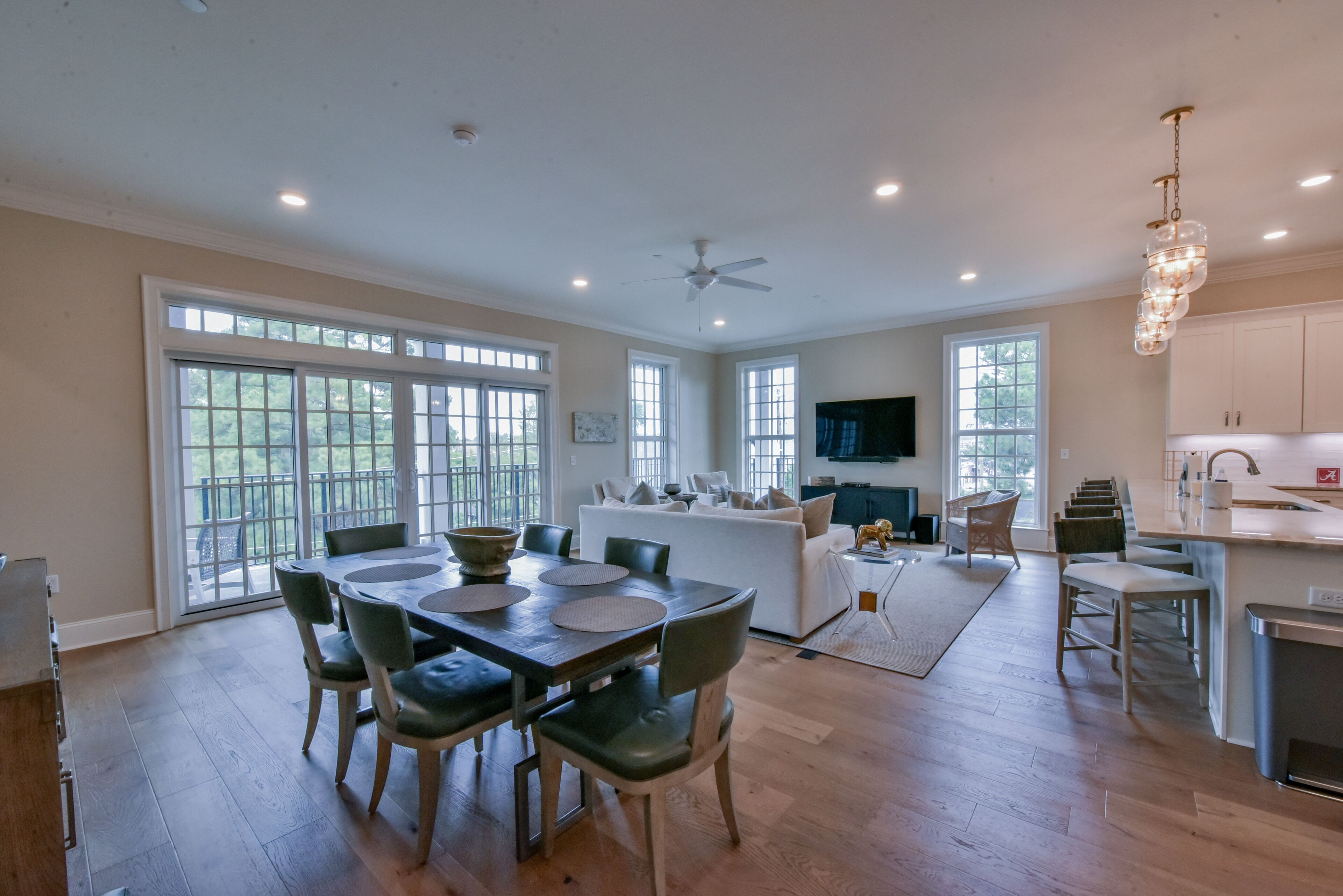 A spacious kitchen with a dining area, large windows, and a ceiling fan.