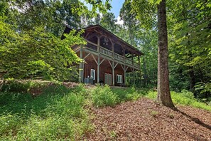 A rustic wooden cabin with a porch, surrounded by dense forest. - A Laurel Haven, with big porches and a log cabin feel. Fireplace. (Brevard)