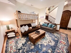 Ein Wohnzimmer mit einem Etagenbett, zwei Sofas, einem Couchtisch und einem gemusterten Teppich.