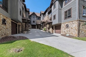A residential street with multi-story houses, stone foundations, and a clear sky. - Luxury Home | Hot Tub | Ski In / Ski Out | Warmers (Whitefish)