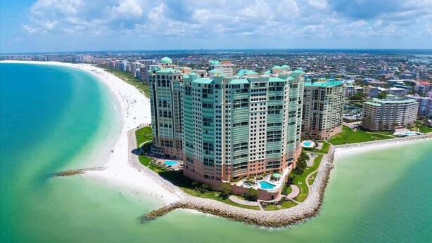 Un hotel di grandi dimensioni con vista sulla spiaggia, numerosi balconi e una zona piscina.