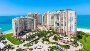 Un complesso alberghiero moderno con diversi edifici, un cortile centrale e vista sulla spiaggia.