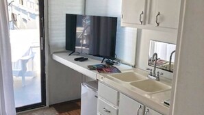 A compact kitchenette with a built-in TV, a sink, and a small refrigerator. - Aqua Lodge Houseboat "Sea Turtle" (Tavernier)