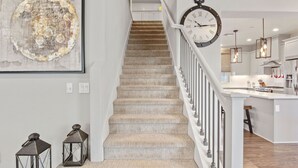 A staircase with a modern design, a kitchen area with a central island, and a clock on the wall. - A diamond in the rough (Rocklin)