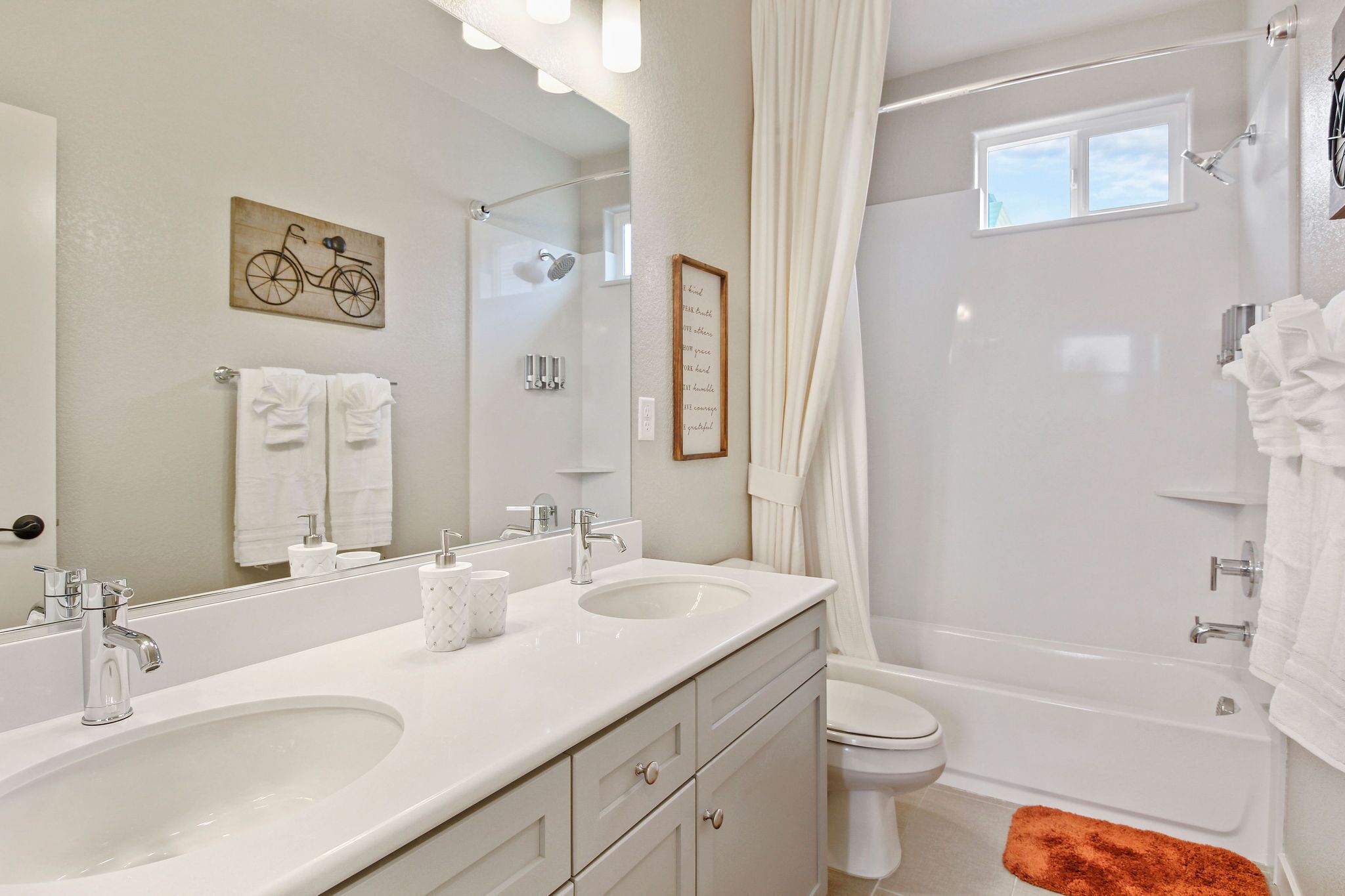 A modern bathroom with two sinks, a toilet, and a bathtub.