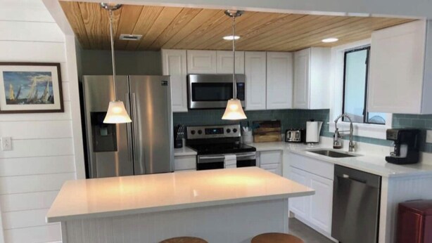 Una cocina moderna con una isla central, electrodomésticos de acero inoxidable y taburetes de madera.