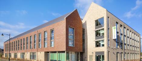 A modern building with a brick facade and large windows, likely a hotel or office space.