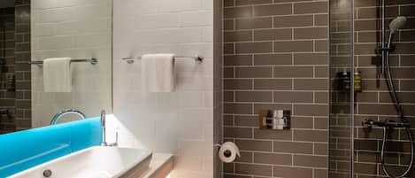 A modern bathroom with a white sink, a blue accent wall, a toilet, and a shower area.