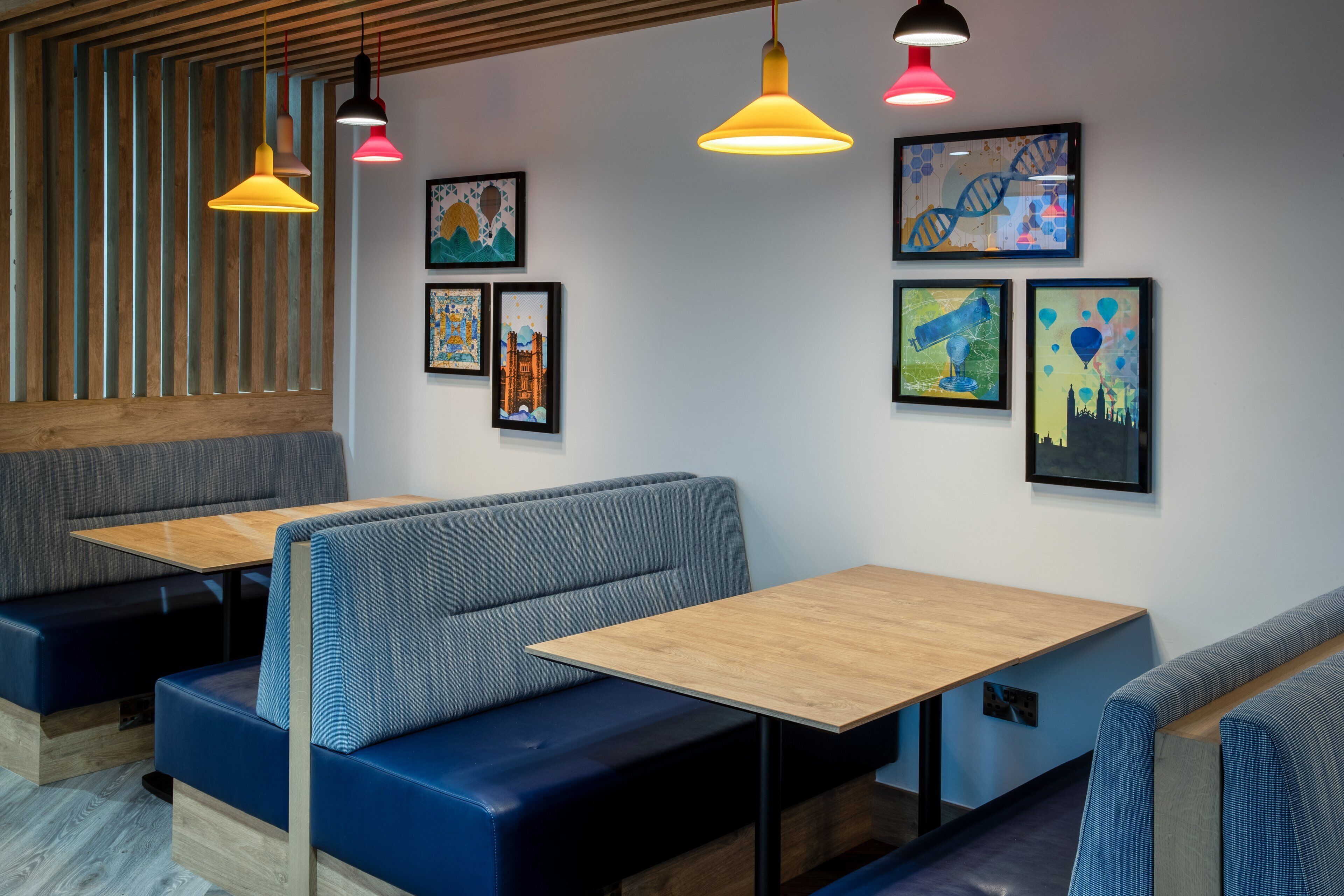 A modern restaurant interior with booths, wooden tables, and colorful pendant lights.