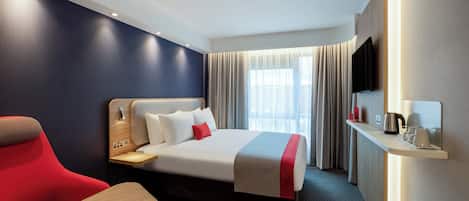 Ein Hotelzimmer mit Bett, Schreibtisch, Stuhl und Fernseher.